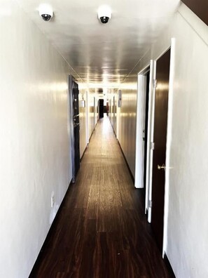 Un couloir doté d’un plancher en bois et de murs métalliques, qui mène à une porte au fond.