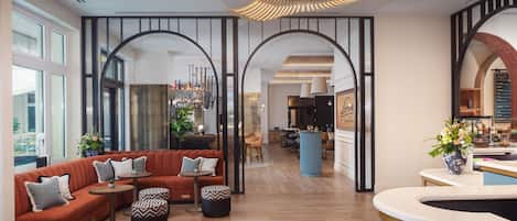 Un vestíbul d'hotel modern amb un sofà vermell, una zona de bar i vistes a la cuina.