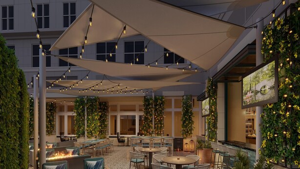Un patio al aire libre con asientos, luces colgantes y vegetación.