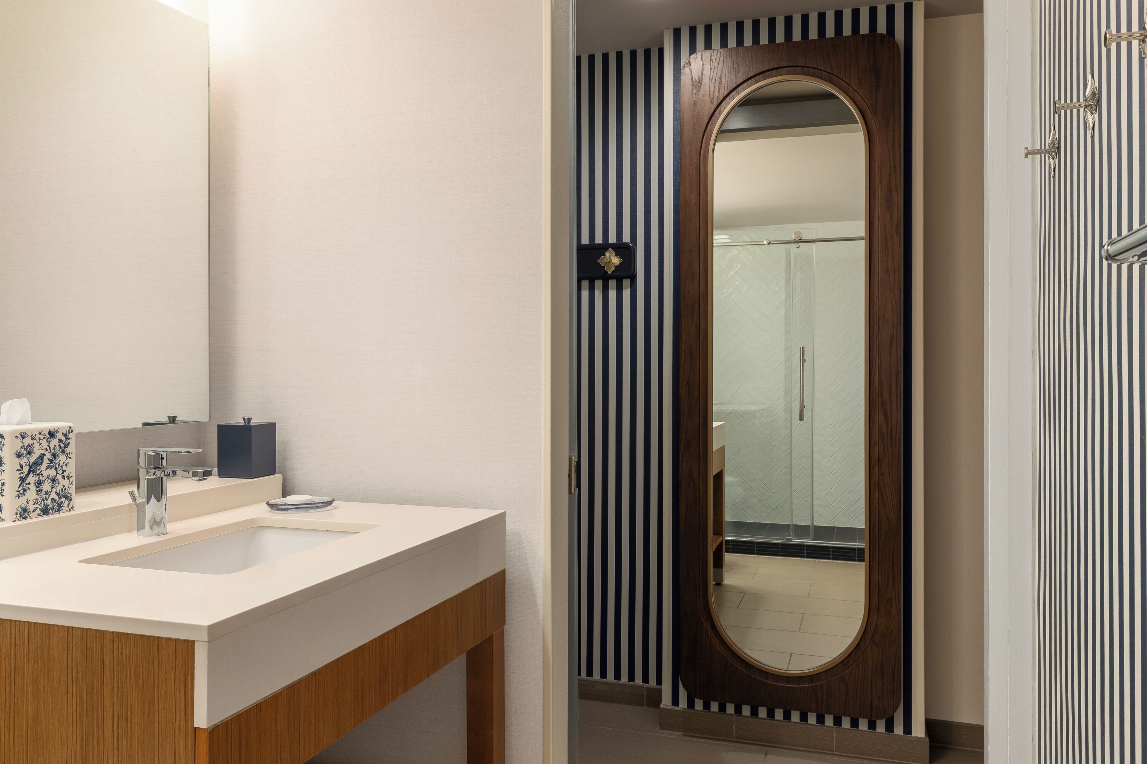 A modern bathroom with a large mirror, a sink, and a shower area.