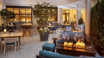 An outdoor seating area with tables, chairs, and a fire feature.