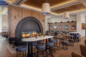 Un área de bar moderna con chimenea, asientos y obras de arte en las paredes.