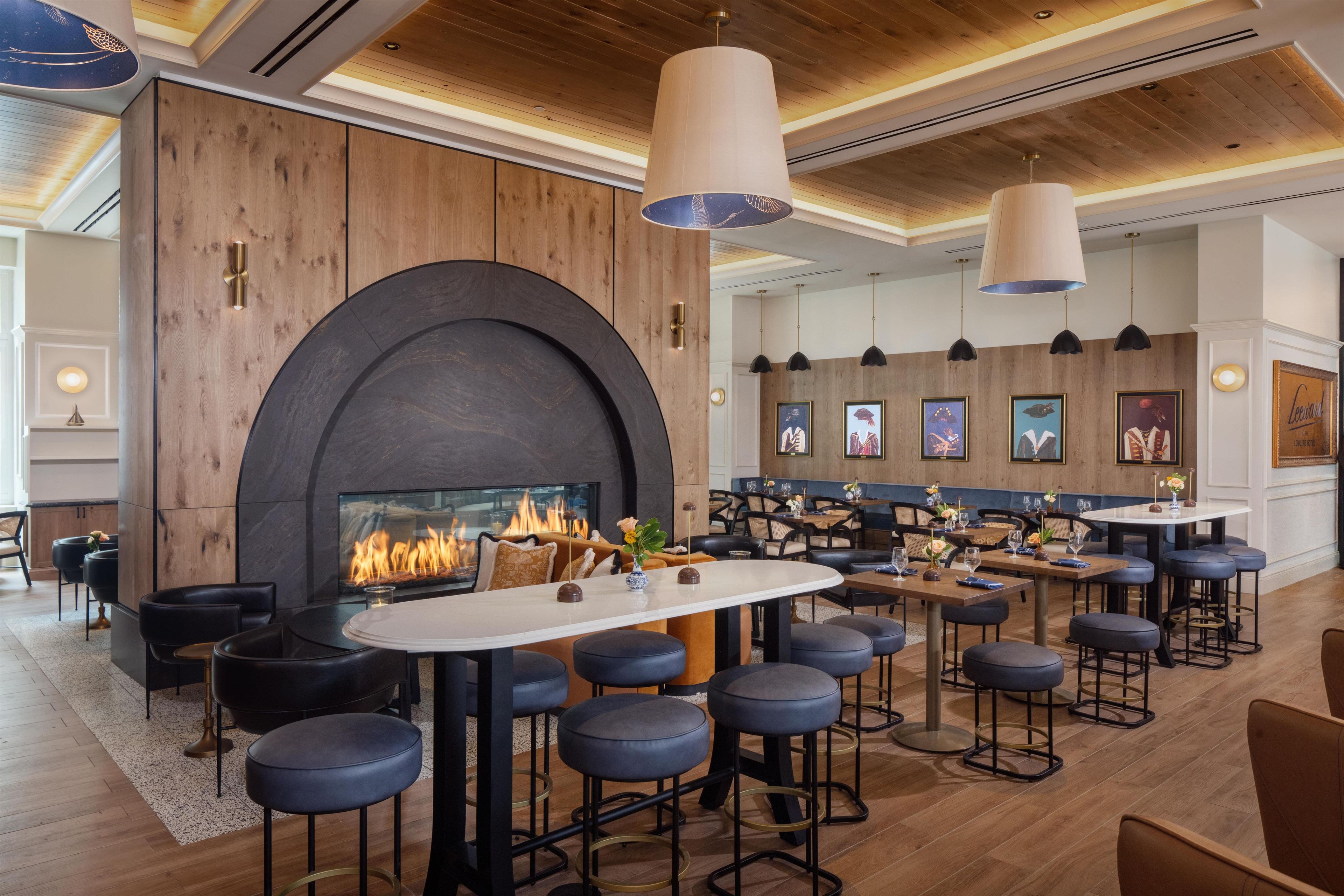 A modern bar area with a fireplace, seating, and artwork on the walls.