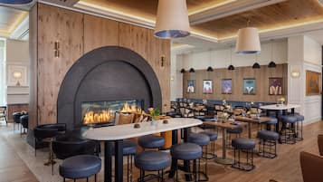 A modern bar area with a fireplace, seating, and artwork on the walls.