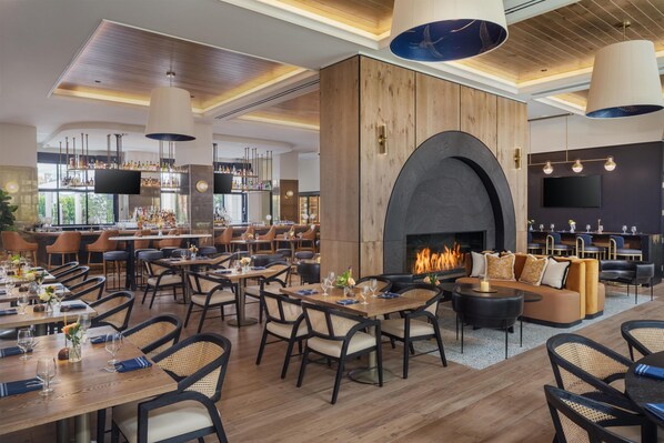 Un restaurante espacioso con varias zonas de comedor, un bar y una chimenea.
