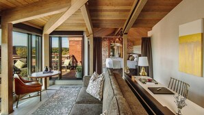 A modern hotel room with a balcony, a dining area, and a large bed with a view of the outdoors. - The Charmant Hotel (La Crosse)