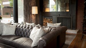 A modern living room with a leather sofa, a fireplace, and a large window. - The Charmant Hotel (La Crosse)