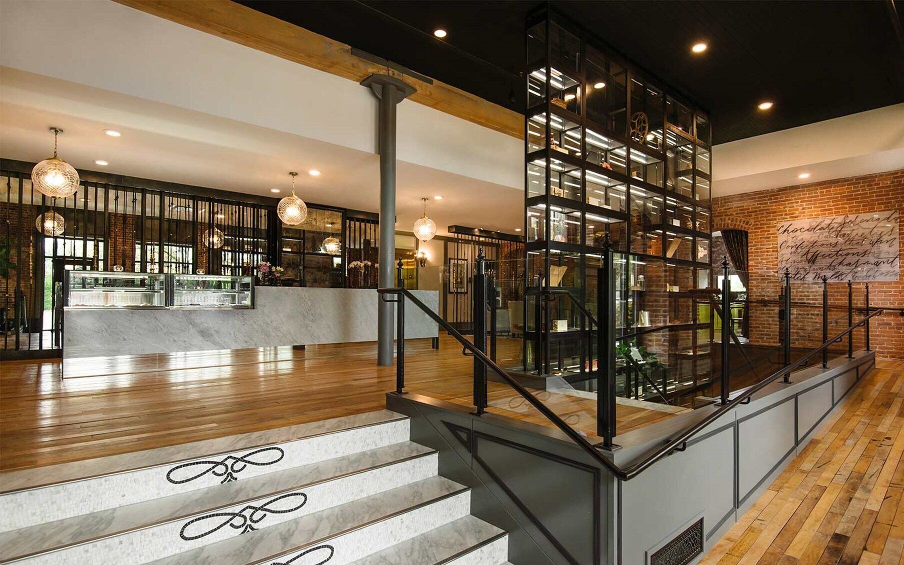 Een modern interieur met een trap, houten vloeren en een barruimte met glazen vitrines.