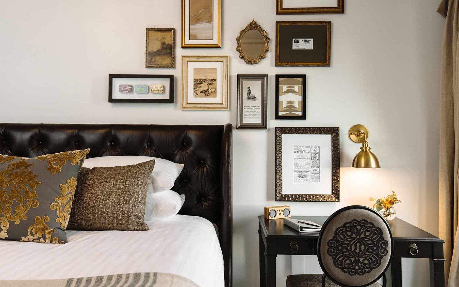Una habitación de hotel con una cama grande, un escritorio con lámpara y varias fotografías enmarcadas en la pared.