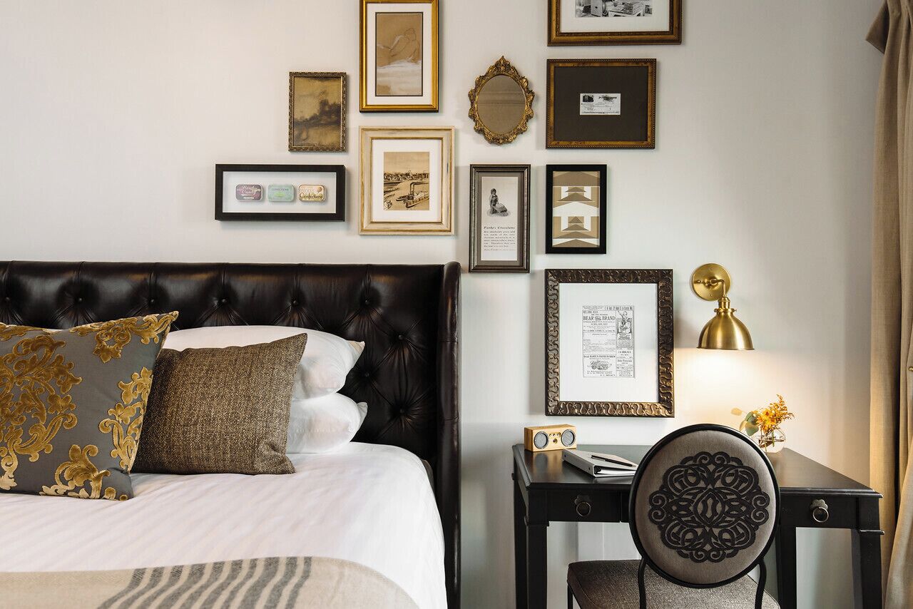 Un dormitorio ordenado con un cabecero capitonado, una mesita de noche con lámpara, y una silla con respaldo decorativo.
