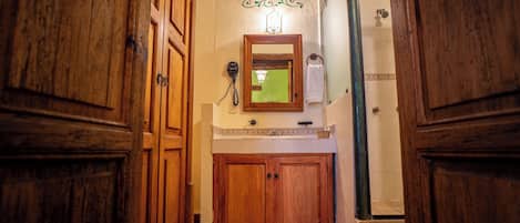 Un estrecho pasillo con puertas de madera, un espejo pequeño y un teléfono instalado en la pared.