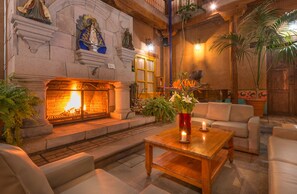 Eine gemütliche Lobby mit Kamin aus Stein, bequemen Sitzgelegenheiten und dekorativen Statuen.