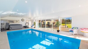 An indoor swimming pool with a view of a patio area. - The Meadows Villa (Christchurch)