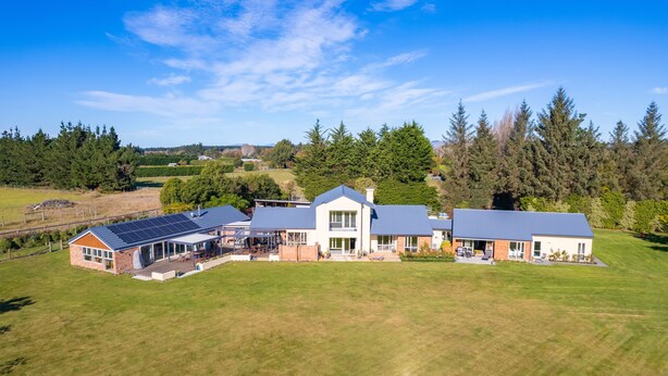A large, modern house with multiple rooms, a covered patio, and a large lawn. - The Meadows Villa (Christchurch)