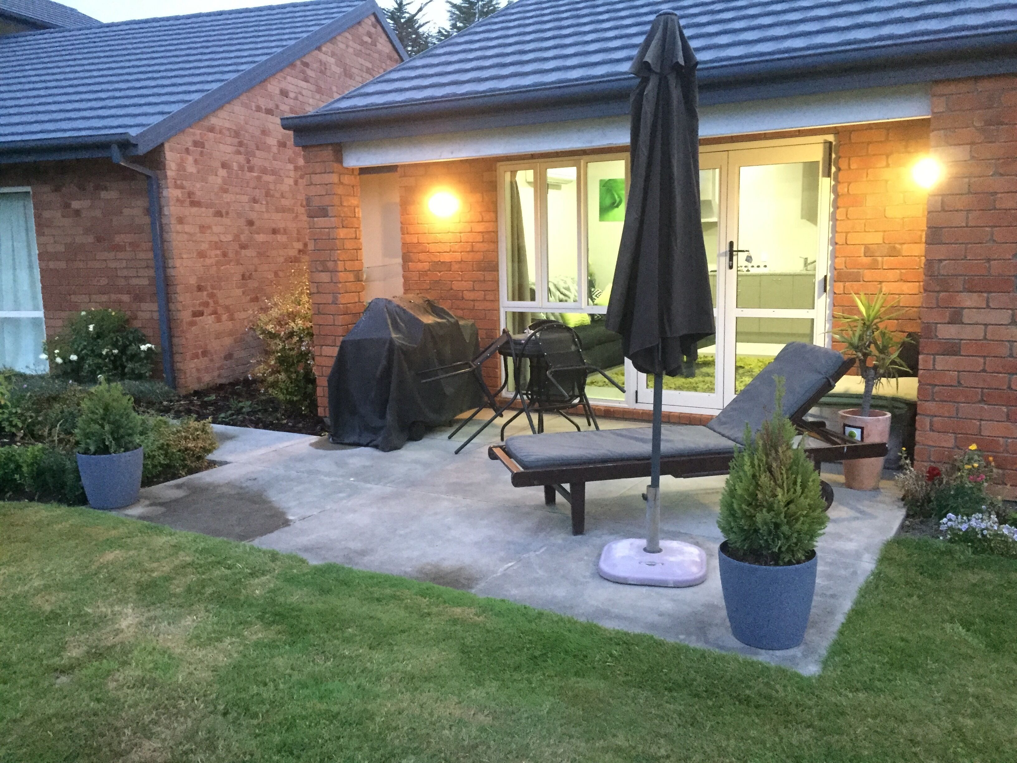 Une terrasse avec un barbecue, du mobilier d’extérieur et des plantes en pot.