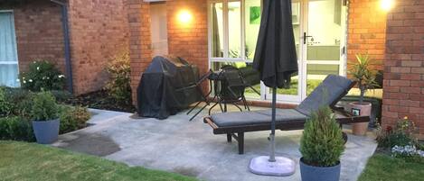Une terrasse avec un barbecue, du mobilier d’extérieur et des plantes en pot.