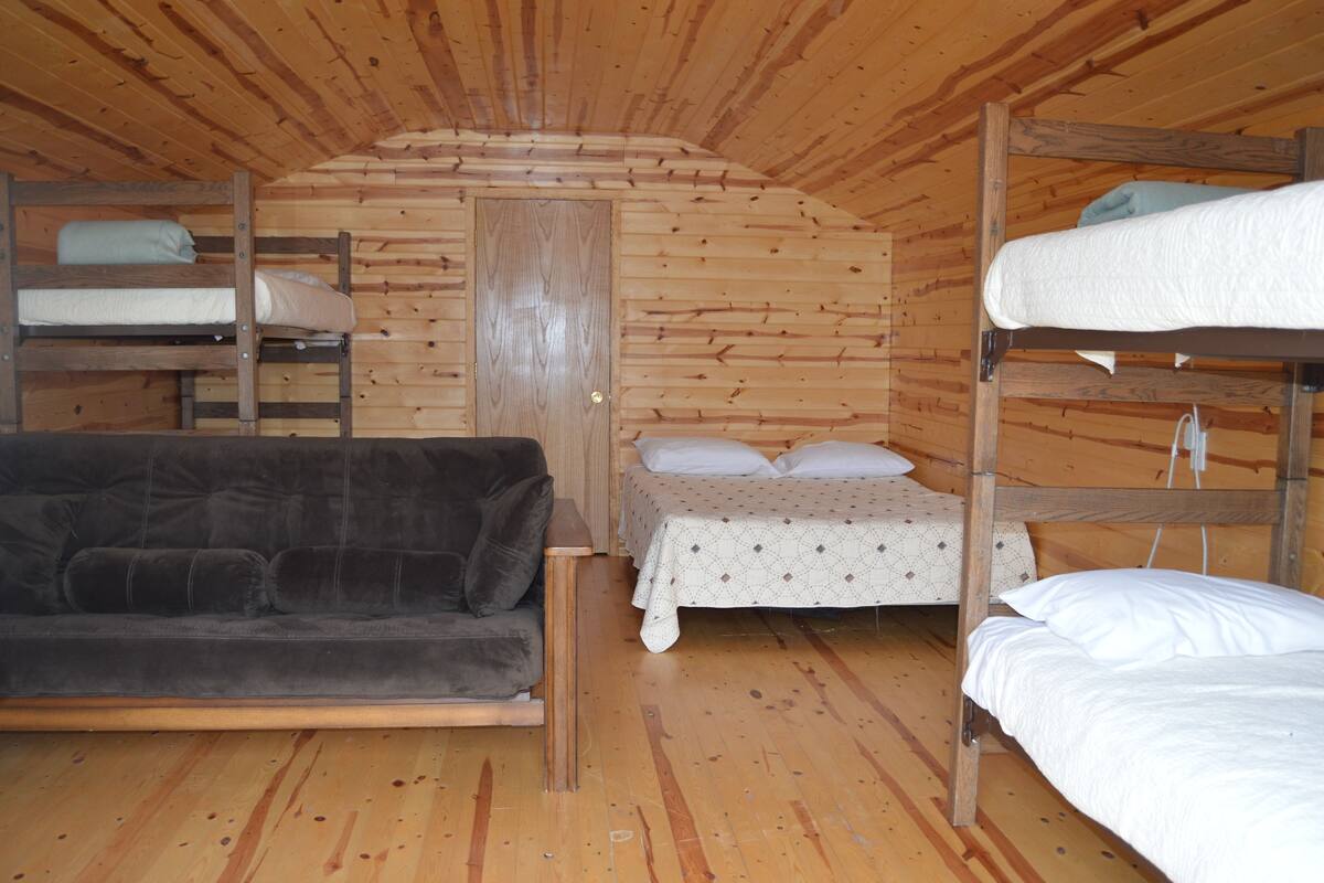 A cabin with bunk beds, a sofa, and a door.