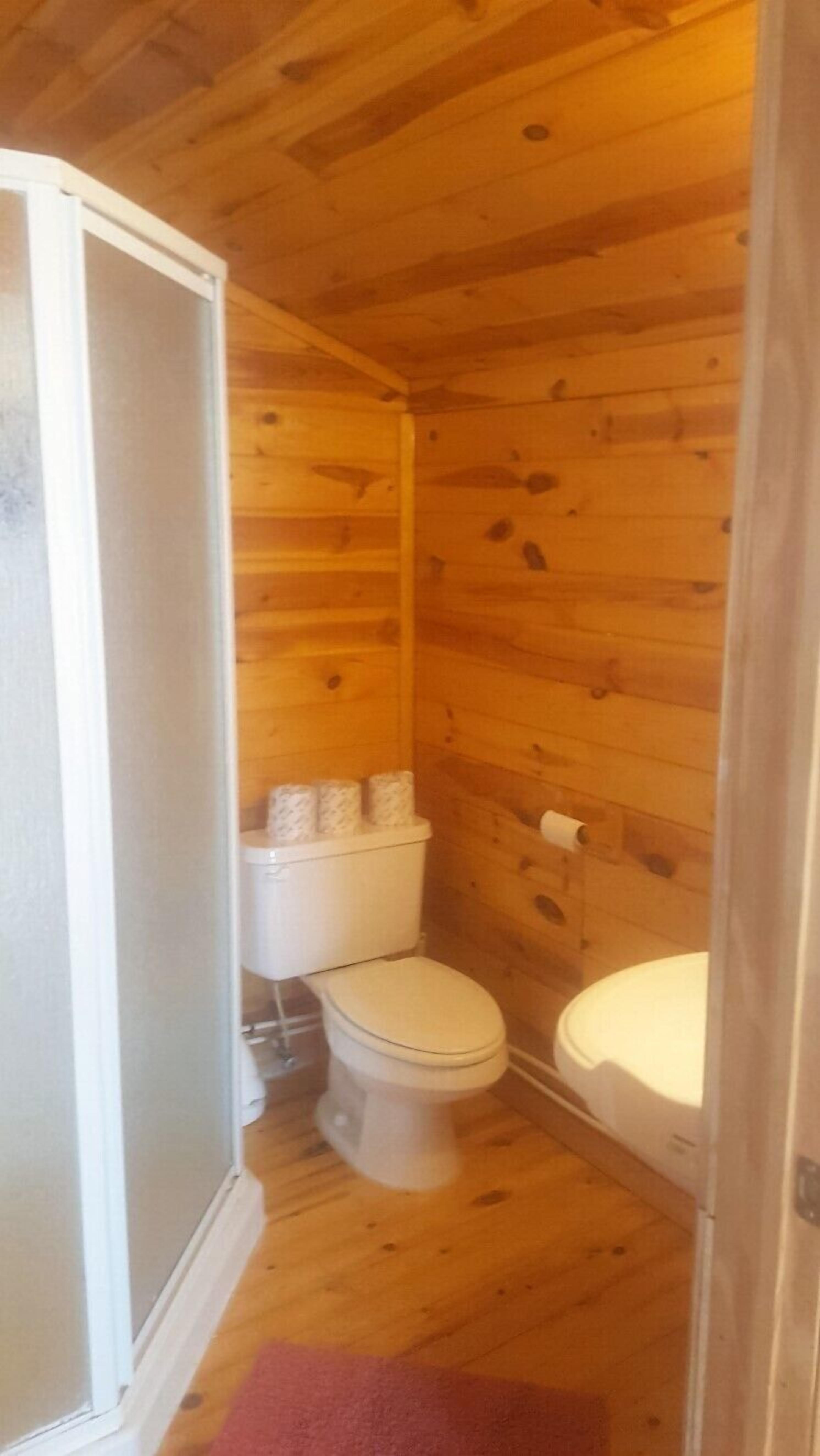 A wooden-paneled bathroom with two toilets and a shower area.