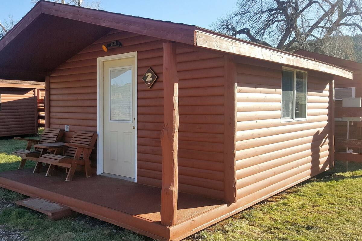 A wooden cabin with a porch, a door, and a window.