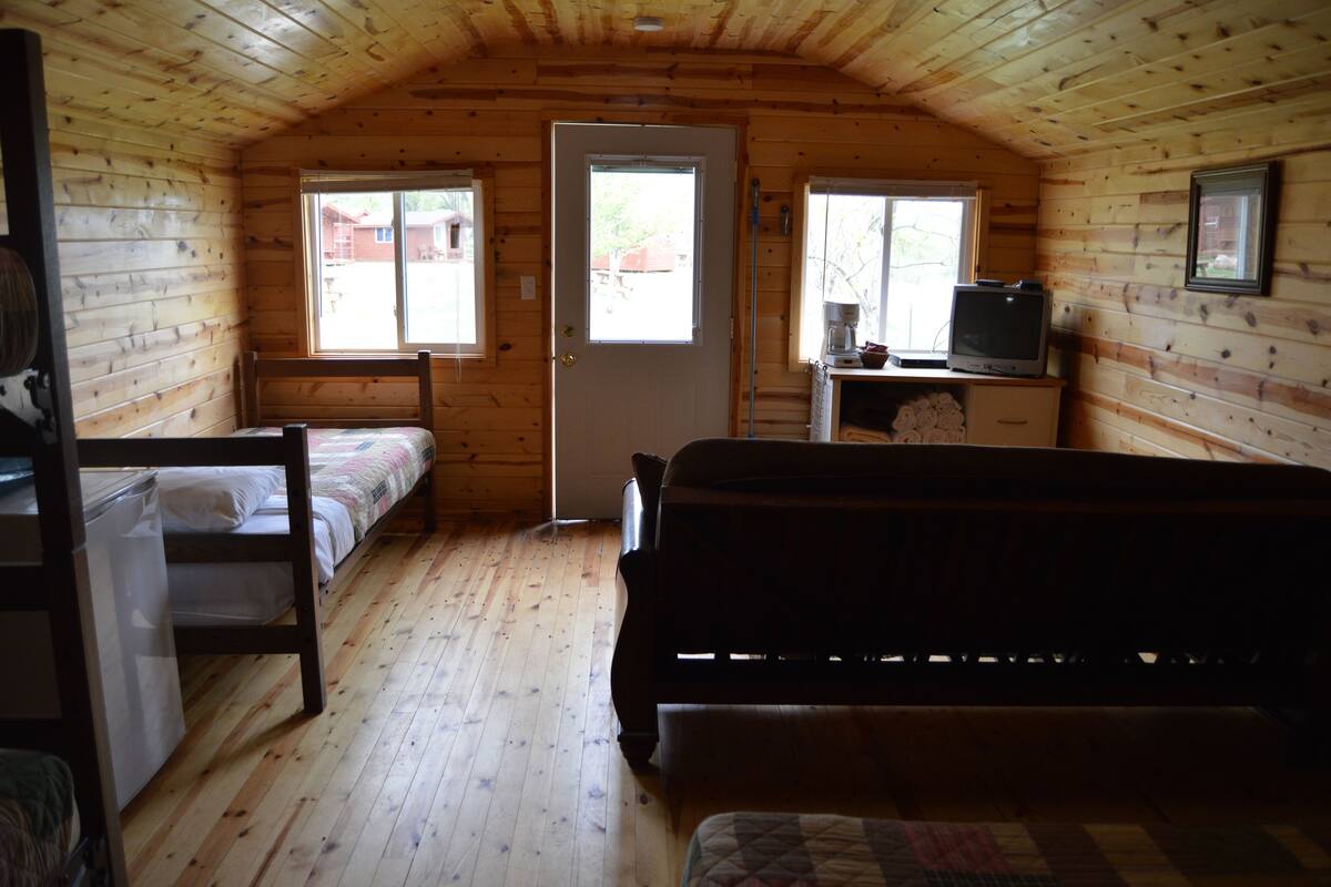 A cabin with two bunk beds, a television, and a door leading to a balcony.