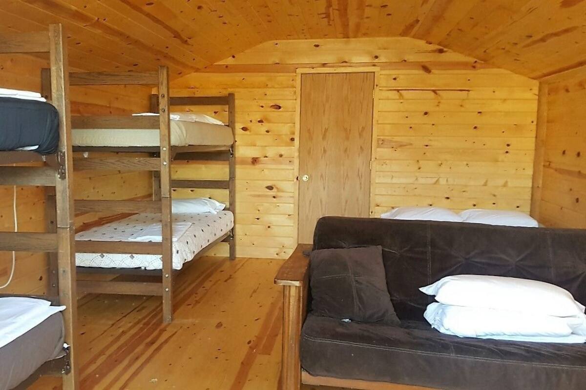 A cabin with bunk beds, a sofa, and a wooden interior.