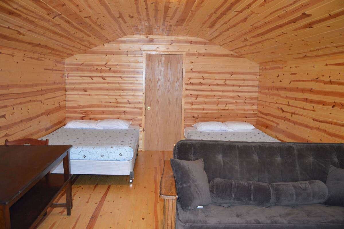 A cabin with two beds, a sofa, and a table.