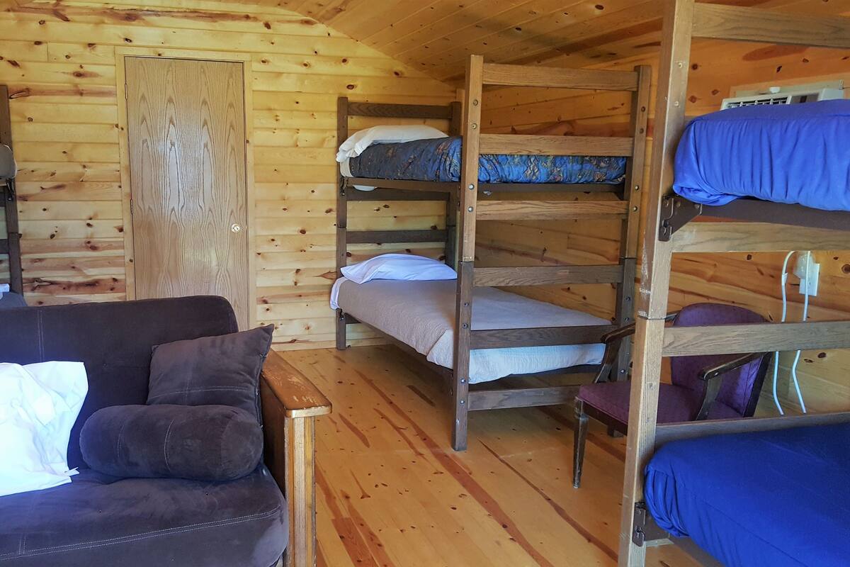 A cabin with bunk beds, a sofa, and a wooden interior.