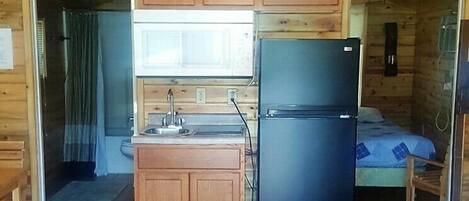 Une petite cabane aux murs en bois et dotée d’un coin cuisine.