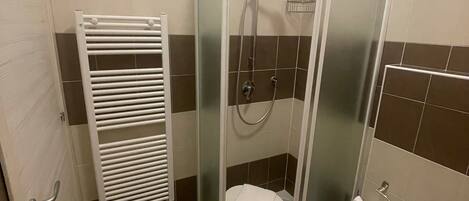 A bathroom with a glass-enclosed shower, a white toilet, a bidet, and a towel rack.