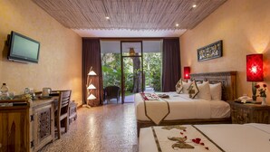 A hotel room with a bed, a desk with a television, a lamp, and a view of the outdoors.