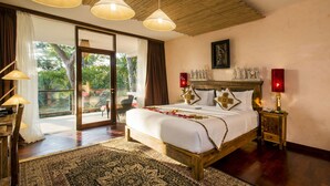 A spacious bedroom with a large bed, a wooden headboard, and a balcony with a view of greenery.