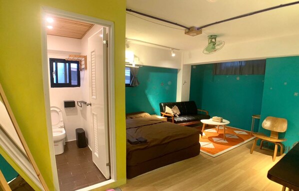A compact hotel room with a bed, a small table, a chair, and a bathroom visible through an open door. - 英倫旅店 - Baker Street Guesthouse (Tainan)