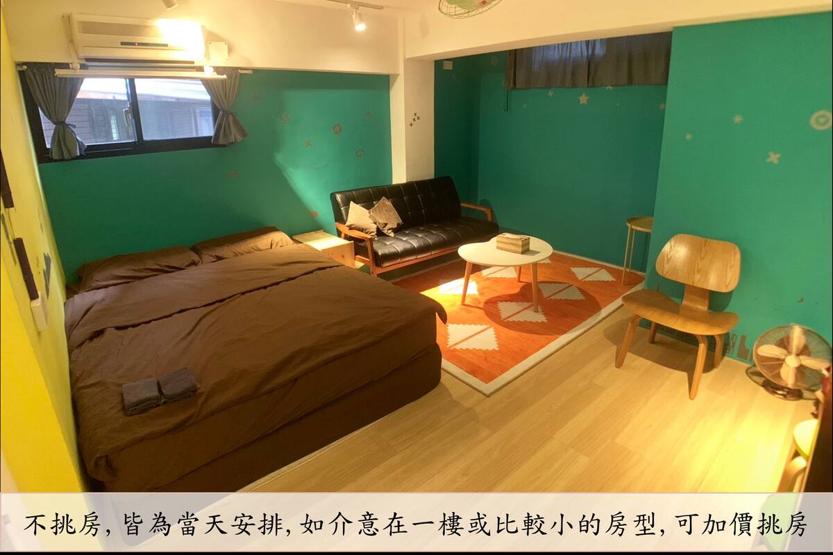 A compact hotel room with a bed, a sofa, a small round table, and a chair.