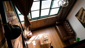 A room with a wooden floor, a leather sofa, a wooden table, and a window with curtains. - 日木民宿 (Tainan)