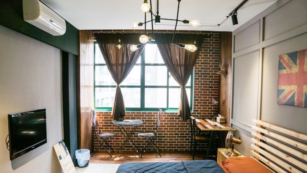 A modern bedroom with a bed, a desk, and a chair. There is a window with curtains, a television, and a painting on the wall. - 日木民宿 (Tainan)