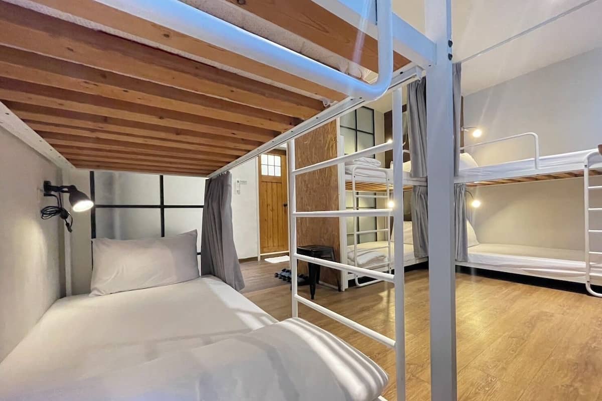 Quarto com beliche, teto de madeira e uma cama simples com cabeceira.