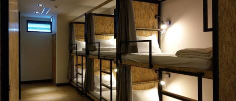 A corridor with bunk beds, wooden walls, and a ceiling with recessed lighting.
