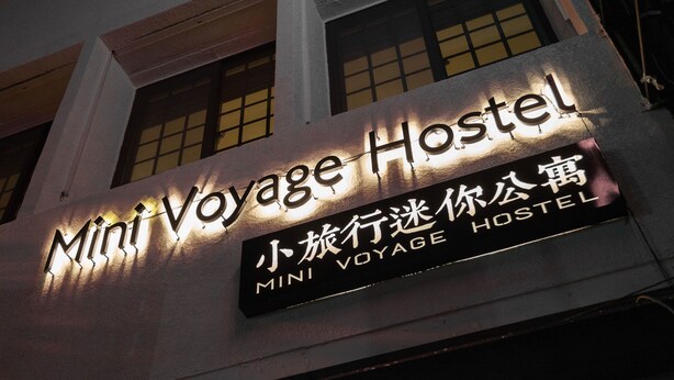 Un edificio con un letrero que dice 'Mini Voyage Hostel' tanto en inglés como en chino.