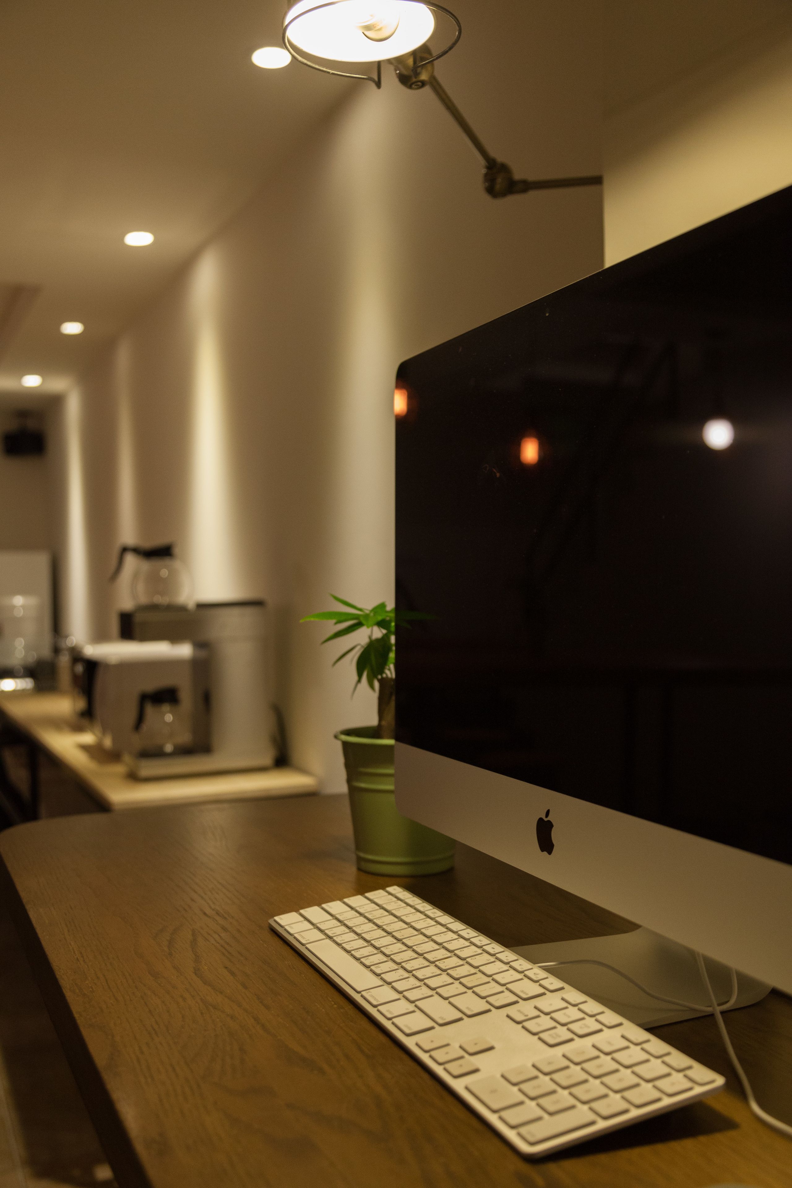 A wooden desk with a white keyboard and an Apple monitor.