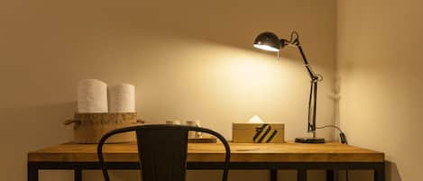 A small workspace with a wooden desk, a black chair, a desk lamp, and a box of tissues.