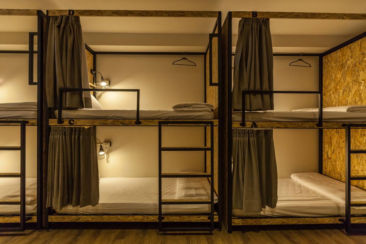 Quarto com beliches, paredes de madeira e luminária pendente.