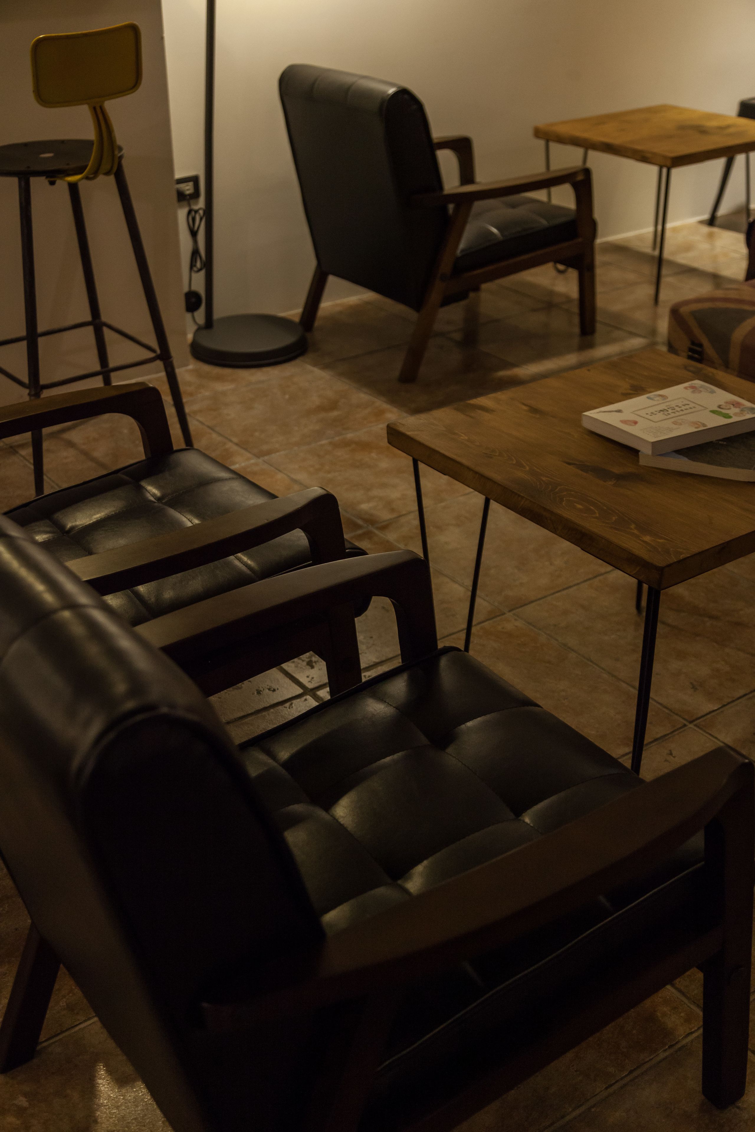 Um quarto com um sofá de couro preto, uma mesa de centro de madeira e uma cadeira preta.