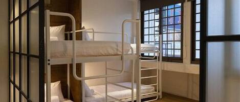 A bunk bed room with a window and a view of buildings outside.
