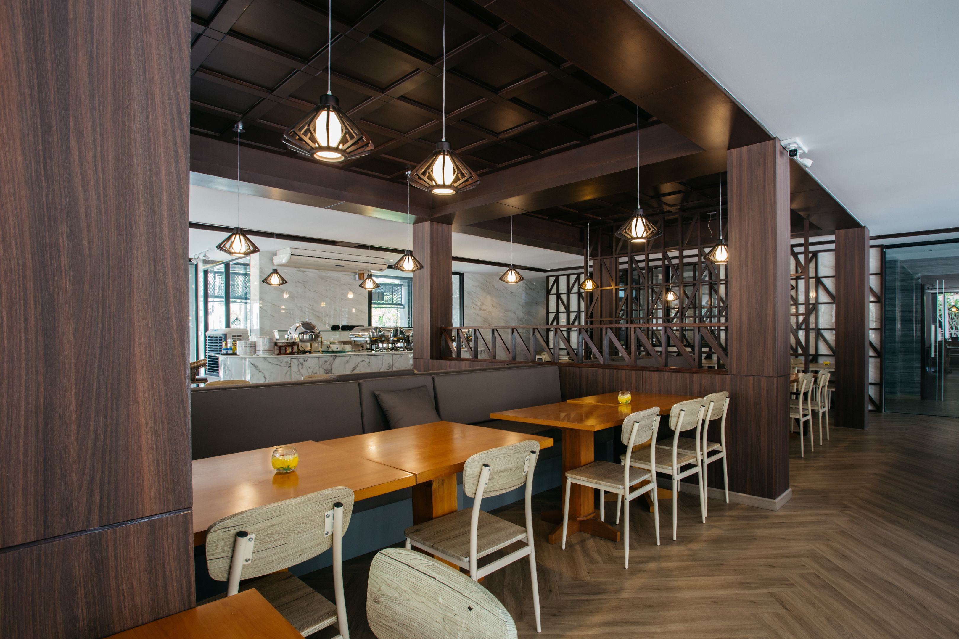Un interior de restaurante moderno con mesas y sillas de madera, lámparas colgantes y una barra de mármol.