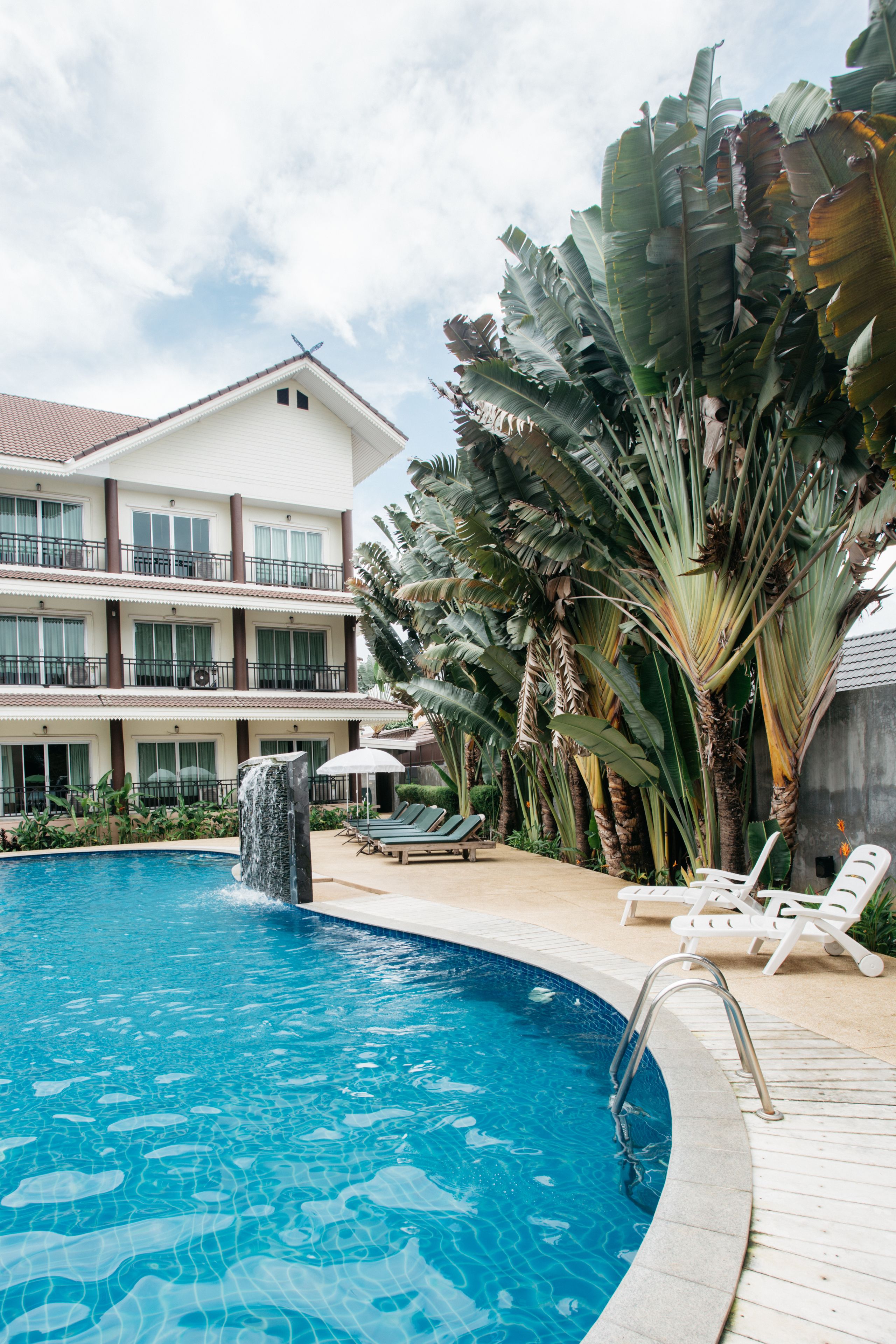 Un hotel con piscina, cascada y exuberante vegetación tropical.