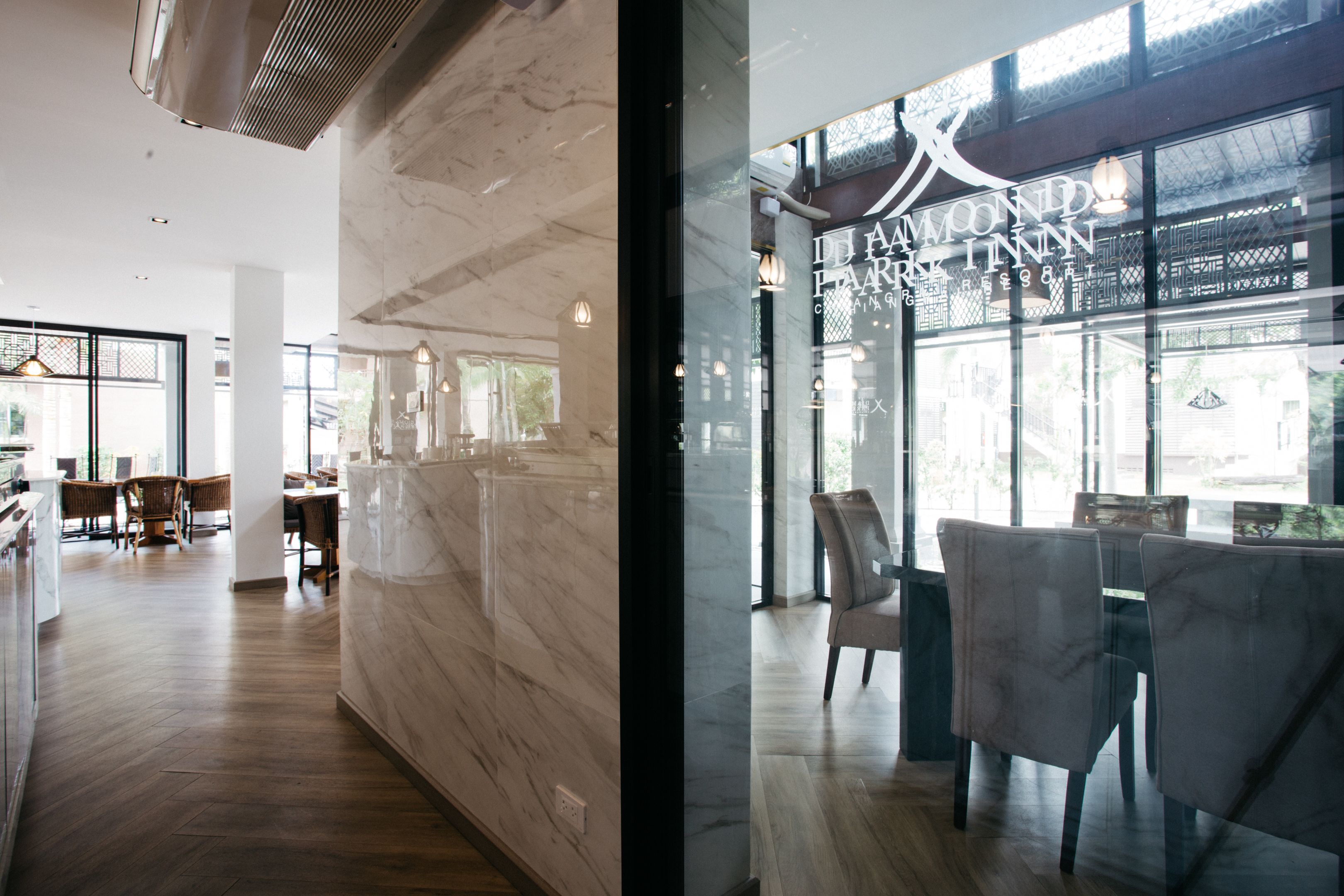 A modern interior with a marble wall, wooden flooring, and a seating area with chairs and tables.