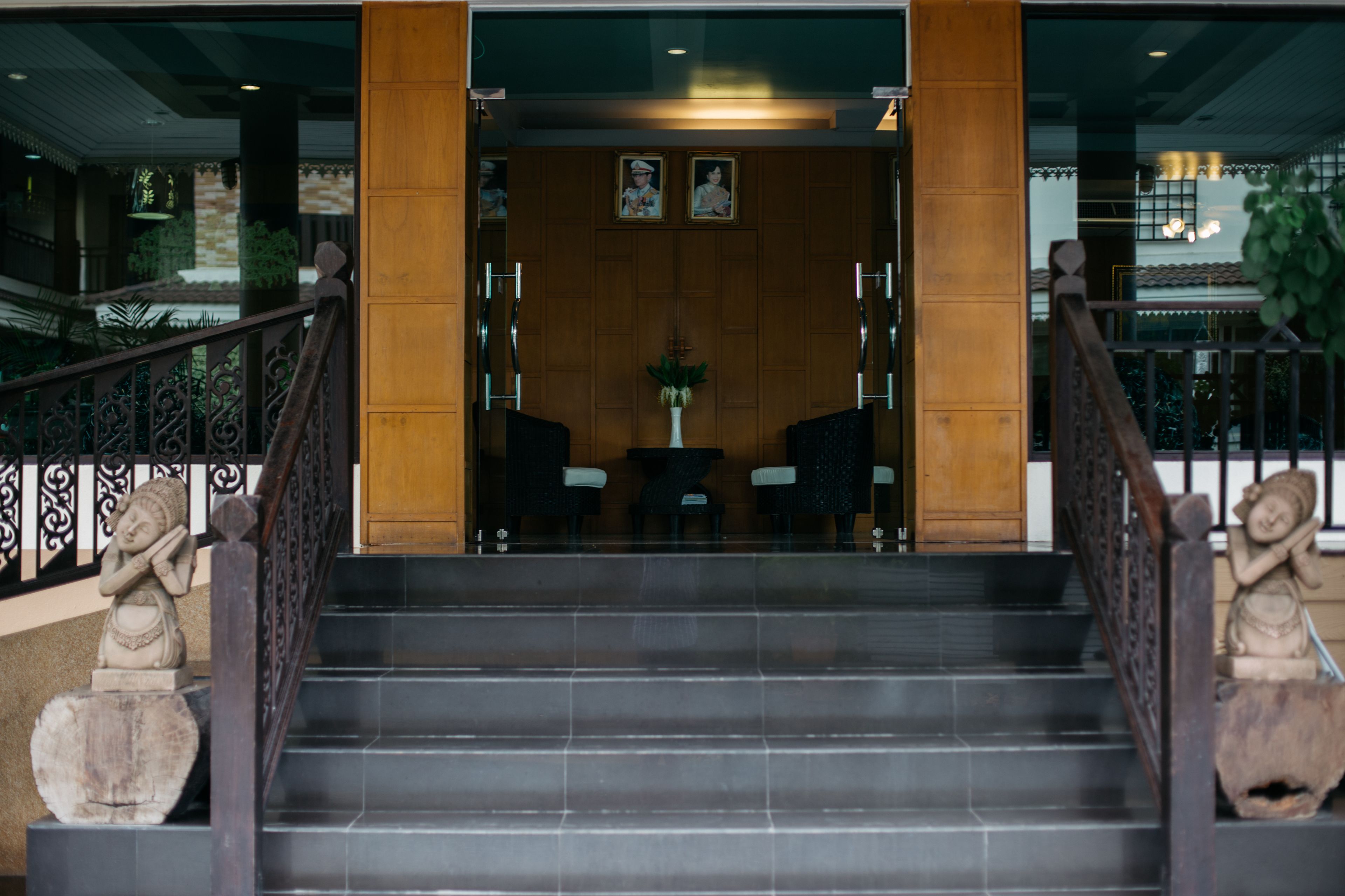 Una escalera conduce a un área de recepción con interior de madera, un mostrador de recepción y una estatua a la izquierda.
