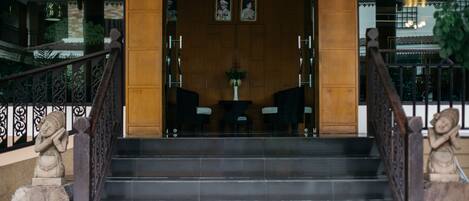 Una escalera conduce a un área de recepción con interior de madera, un mostrador de recepción y una estatua a la izquierda.