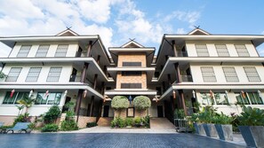 A multi-story hotel with a central entrance, balconies, and a tiled courtyard.