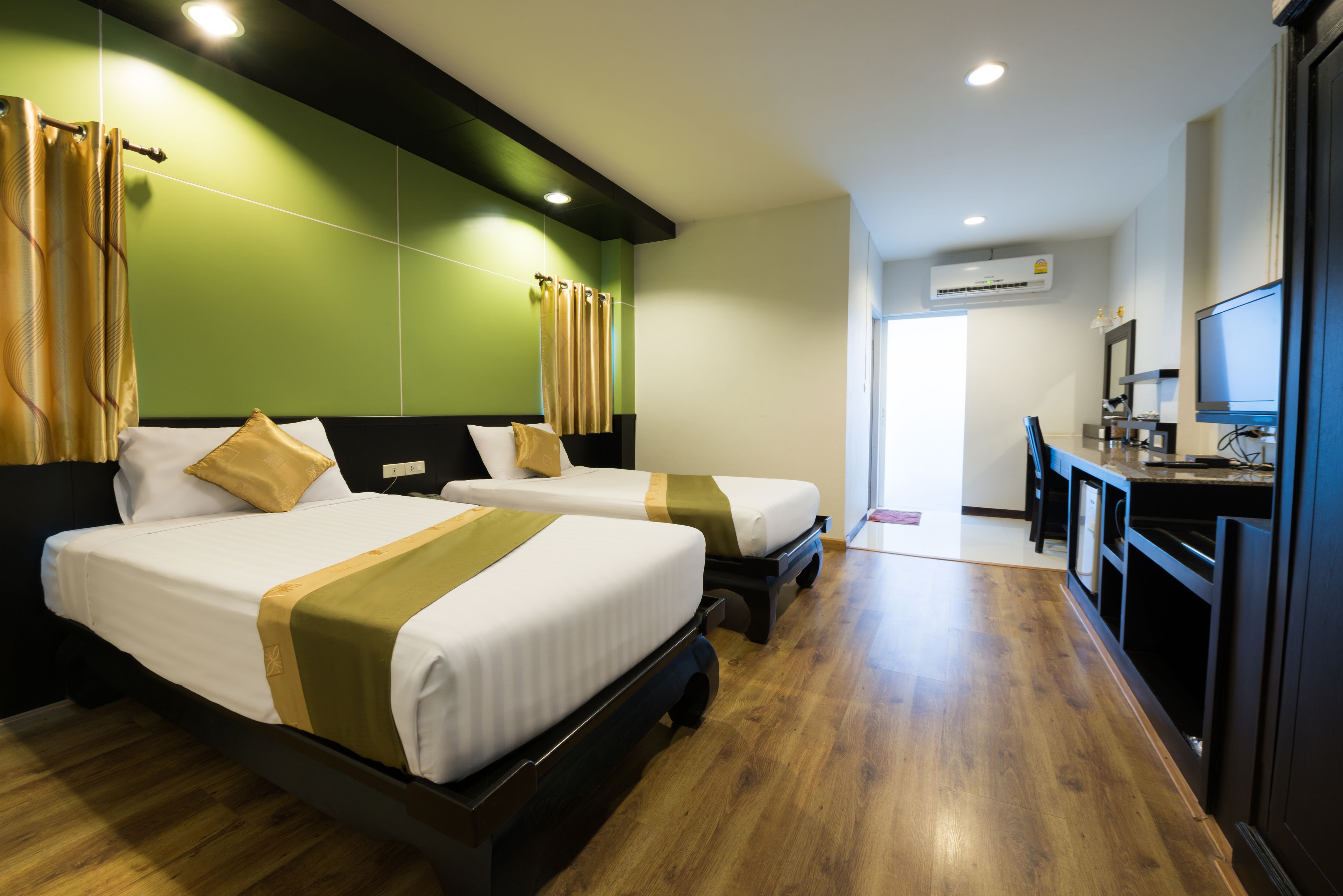 A hotel room with two beds, a desk, and a television.